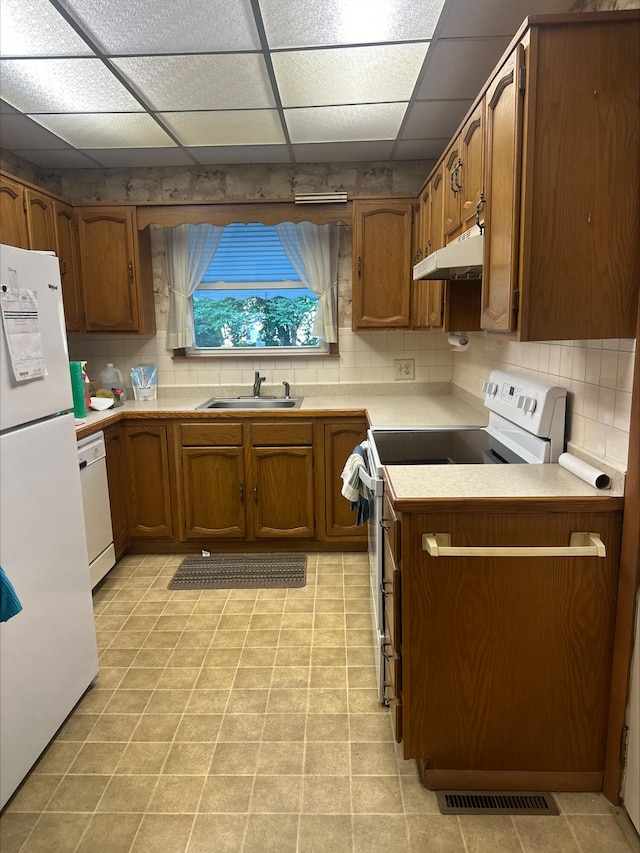 1414 N Clay Ave, Springfield, MO 65802 - kitchen featuring white appliances, under cabinet range hood, brown cabinetry, a paneled ceiling, and backsplash
