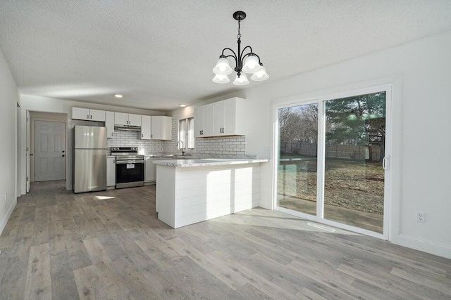 502 S Walnut St, Walnut Grove, MO 65770 - kitchen featuring appliances with stainless steel finishes, under cabinet range hood, a chandelier, light wood finished floors, and a peninsula