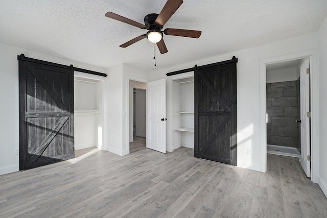 502 S Walnut St, Walnut Grove, MO 65770 - unfurnished bedroom featuring a barn door, wood finished floors, a textured ceiling, ceiling fan, and connected bathroom