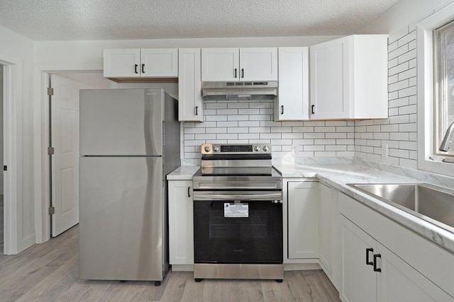 502 S Walnut St, Walnut Grove, MO 65770 - kitchen with appliances with stainless steel finishes, under cabinet range hood, white cabinets, light wood finished floors, and a textured ceiling