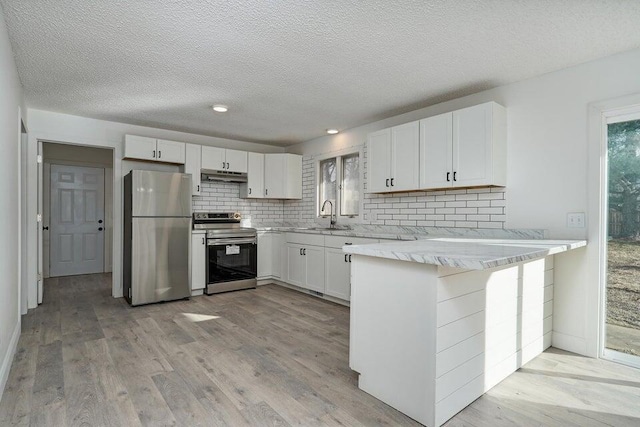 502 S Walnut St, Walnut Grove, MO 65770 - kitchen featuring stainless steel appliances, under cabinet range hood, a peninsula, backsplash, and a textured ceiling