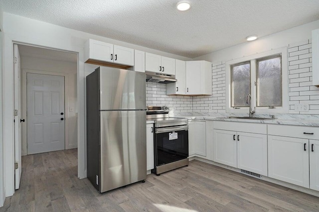 502 S Walnut St, Walnut Grove, MO 65770 - kitchen with appliances with stainless steel finishes, under cabinet range hood, a textured ceiling, white cabinets, and decorative backsplash