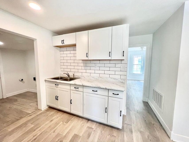 900 N Eagle Ave, Springfield, MO 65802 - kitchen with light wood-type flooring, backsplash, and white cabinetry