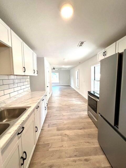 900 N Eagle Ave, Springfield, MO 65802 - kitchen with appliances with stainless steel finishes, white cabinetry, light wood-style flooring, and backsplash