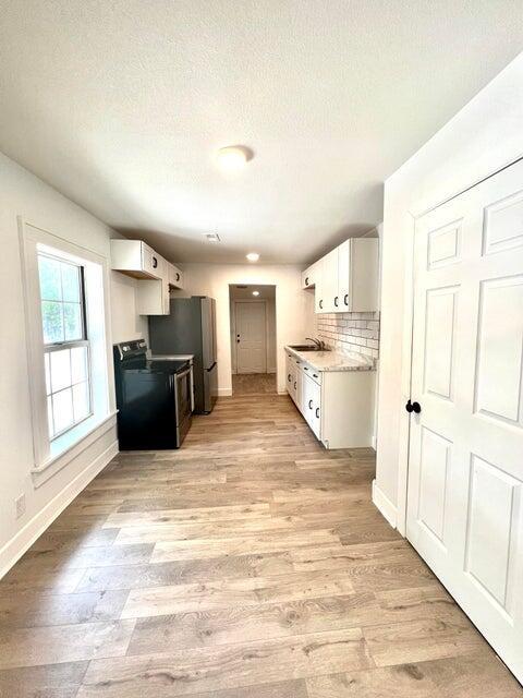 900 N Eagle Ave, Springfield, MO 65802 - kitchen with electric range oven, light wood-style flooring, light countertops, white cabinets, and a textured ceiling