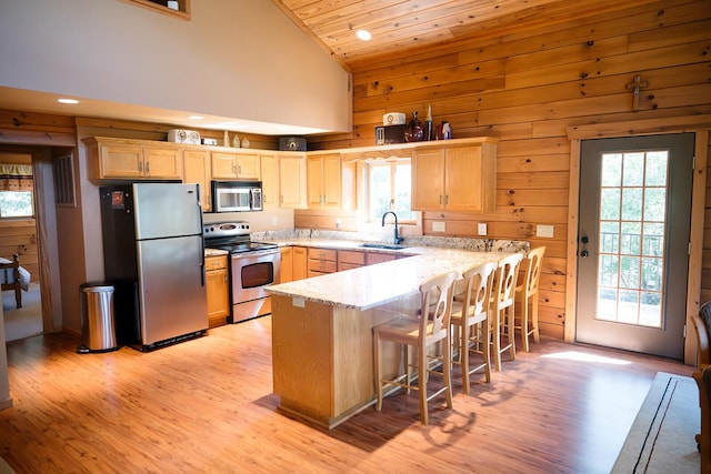 20816 Valley View Trl, Wheatland, MO 65779 - kitchen featuring stainless steel appliances, light brown cabinetry, a peninsula, wooden walls, and lofted ceiling