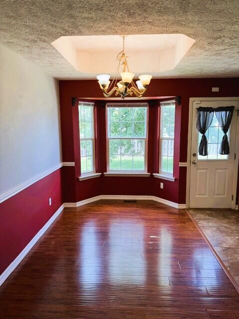 1359 W Stone House Rd, Nixa, MO 65714 - unfurnished dining area featuring a textured ceiling, hardwood / wood-style flooring, a chandelier, and a raised ceiling