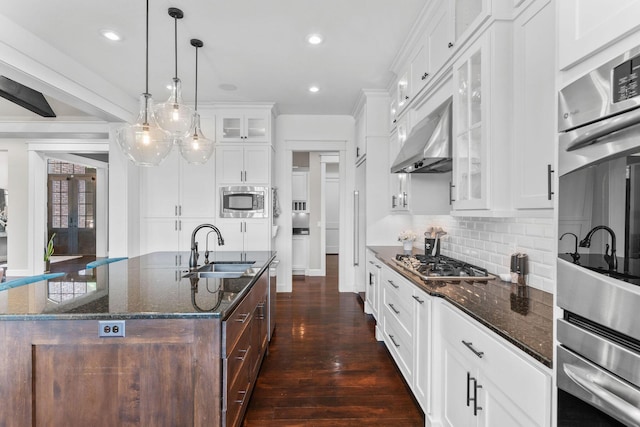 6421 S Valley Brook Ct, Springfield, MO 65810 - kitchen featuring stainless steel appliances, dark stone counters, tasteful backsplash, a center island with sink, and white cabinetry