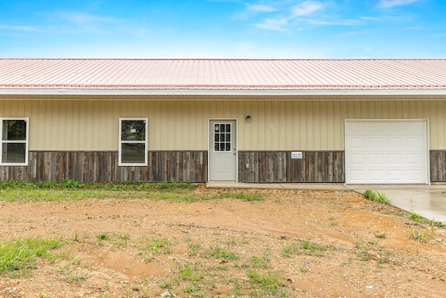 view of exterior entry featuring a metal roof, concrete driveway, and a garage