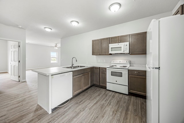 kitchen featuring white appliances, a peninsula, light wood finished floors, and light countertops