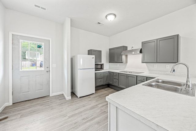 kitchen featuring freestanding refrigerator, stainless steel microwave, black electric cooktop, gray cabinetry, and under cabinet range hood