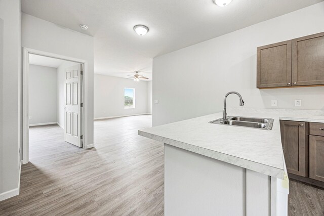 kitchen with a peninsula, light wood-type flooring, light countertops, and a ceiling fan