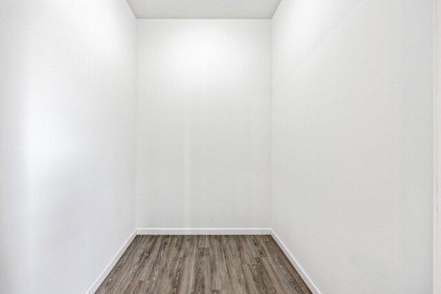 unfurnished room with dark wood-style flooring and baseboards