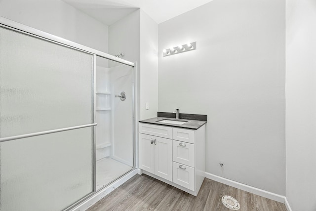 bathroom featuring wood finished floors, a shower stall, and vanity