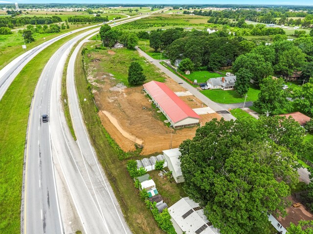 aerial view of property and surrounding area with a main thoroughfare and a tree filled landscape