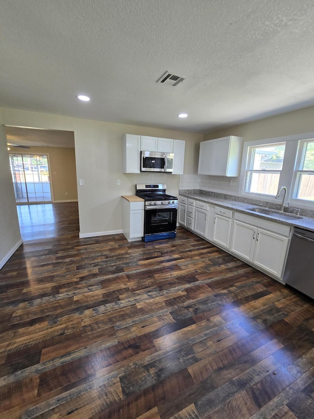 1008 3rd St, Monett, MO 65708 - kitchen featuring stainless steel appliances, dark wood-style floors, a textured ceiling, white cabinetry, and light countertops