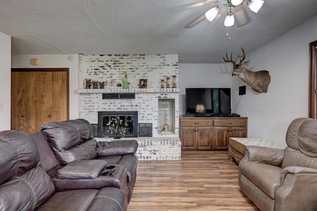 2148 Carrie St, Carthage, MO 64836 - living area with wood finished floors, a ceiling fan, a textured ceiling, and a brick fireplace