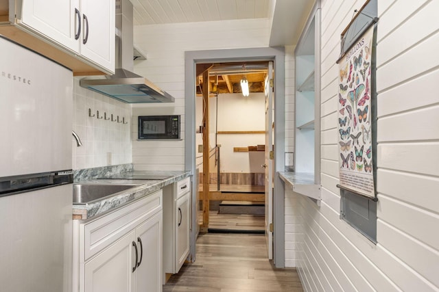 537 Watson Rd, Branson, MO 65616 - kitchen featuring exhaust hood, freestanding refrigerator, black microwave, light wood-type flooring, and white cabinets