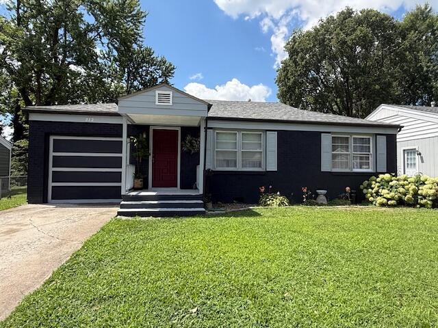212 W Lindberg St, Springfield, MO 65807 - single story home with an attached garage, concrete driveway, and a front lawn