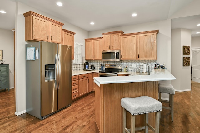 1376 N Sandy Creek Cir # 1, Nixa, MO 65714 - kitchen featuring stainless steel appliances, a peninsula, dark wood finished floors, backsplash, and a breakfast bar area