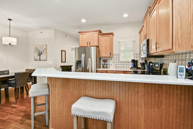 1376 N Sandy Creek Cir # 1, Nixa, MO 65714 - kitchen featuring stainless steel appliances, a peninsula, decorative backsplash, dark wood-style flooring, and a breakfast bar