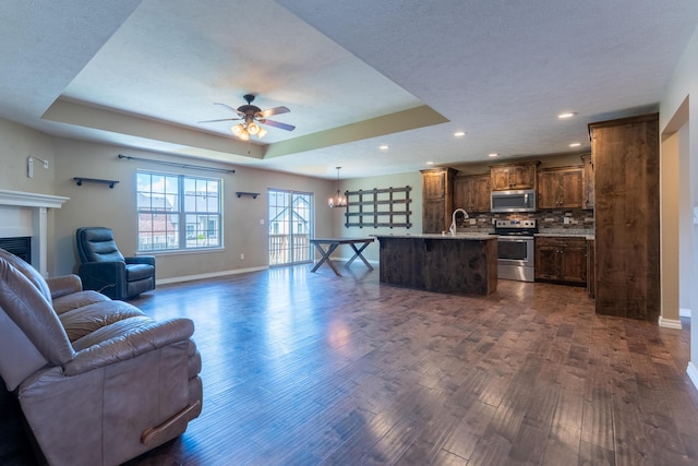 865 E Striper Dr, Nixa, MO 65714 - living area with ceiling fan, dark wood-style flooring, a tray ceiling, a fireplace, and recessed lighting