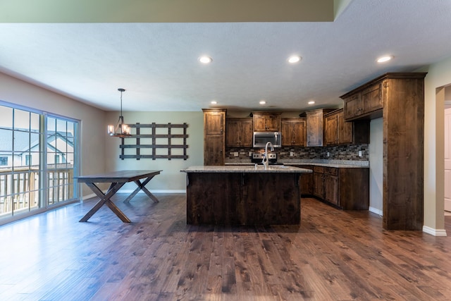 865 E Striper Dr, Nixa, MO 65714 - kitchen with stainless steel microwave, dark wood-type flooring, backsplash, recessed lighting, and a kitchen island with sink
