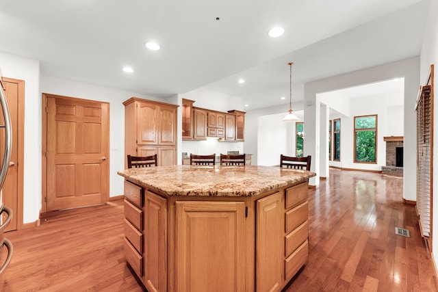 201 Silver Oak Ln, Branson West, MO 65737 - kitchen with light wood-style flooring, a kitchen island, light stone counters, pendant lighting, and recessed lighting