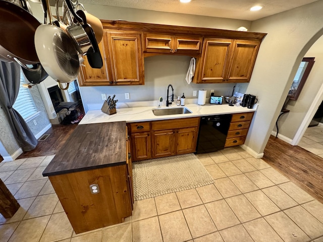 5537 S Pinehurst Ave, Springfield, MO 65810 - kitchen with black dishwasher, arched walkways, brown cabinets, light tile patterned floors, and recessed lighting