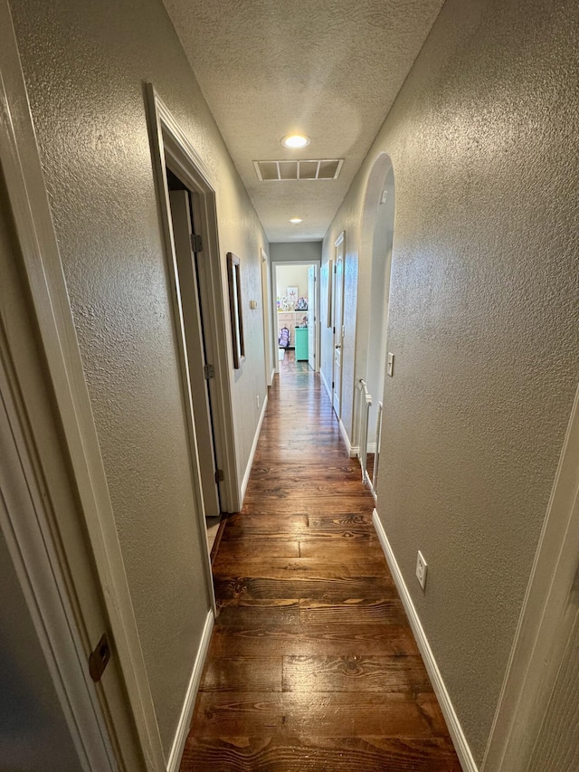 5537 S Pinehurst Ave, Springfield, MO 65810 - corridor featuring a textured wall, dark wood-style floors, a textured ceiling, and arched walkways