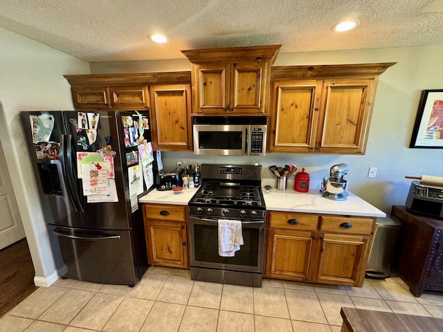 5537 S Pinehurst Ave, Springfield, MO 65810 - kitchen with stainless steel microwave, fridge with ice dispenser, black range with gas cooktop, brown cabinetry, and a textured ceiling