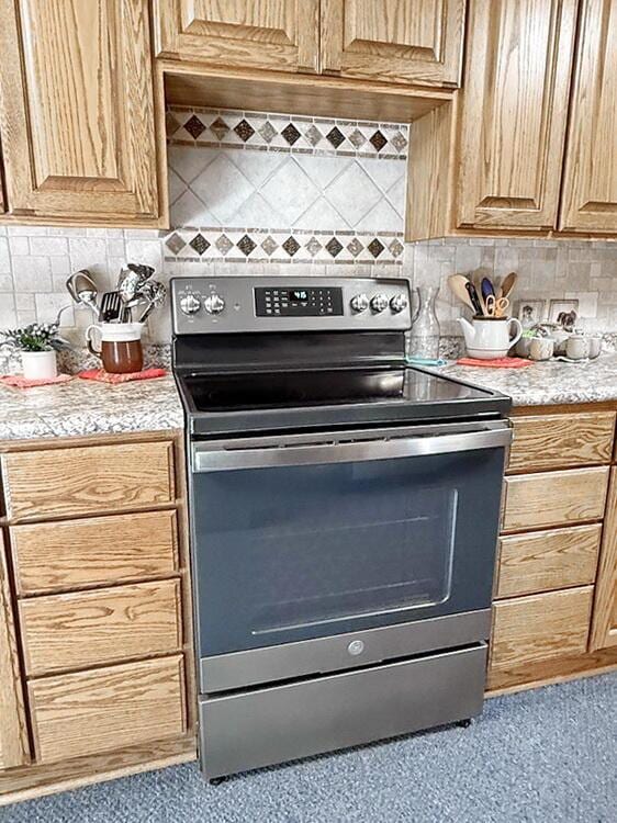 16610 S 1375th Rd, Nevada, MO 64772 - kitchen with stainless steel electric range, light countertops, backsplash, and carpet floors