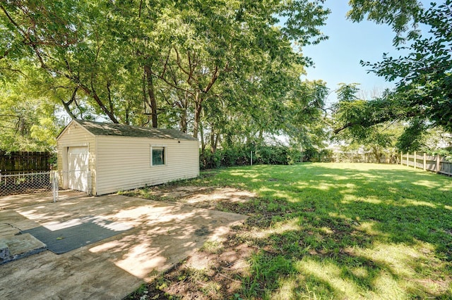 1739 S S Ave, Springfield, MO 65807 - fenced backyard with a detached garage, an outbuilding, a patio area, concrete driveway, and view of wooded area