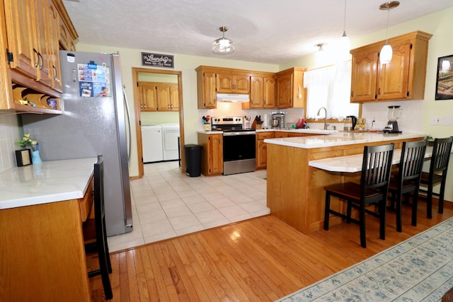 576 S Barnstable, Nixa, MO 65714 - kitchen featuring stainless steel appliances, under cabinet range hood, washer and dryer, a peninsula, and light countertops