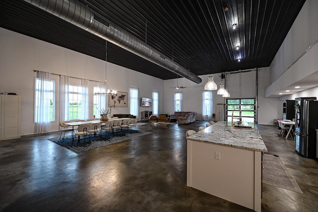 30950 E 54th Hwy, El Dorado Springs, MO 64744 - kitchen with concrete flooring, a high ceiling, open floor plan, a center island, and freestanding refrigerator