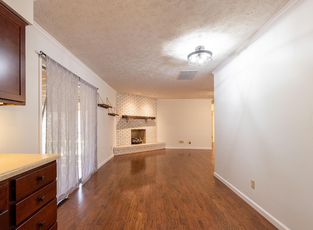 2924 S Roanoke Ave, Springfield, MO 65807 - unfurnished living room featuring a textured ceiling, dark wood-type flooring, a brick fireplace, and ornamental molding