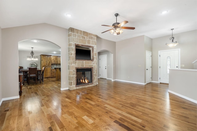 1545 N Oakfair Pl, Springfield, MO 65802 - living area with arched walkways, ceiling fan, vaulted ceiling, wood finished floors, and a stone fireplace
