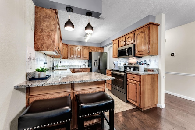 150 Sunken Forest Dr Unit 10-253, Forsyth, MO 65653 - kitchen featuring appliances with stainless steel finishes, a peninsula, brown cabinets, and a textured ceiling