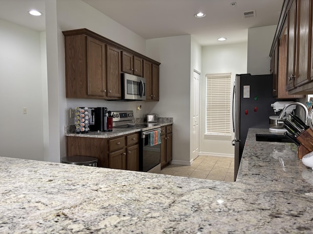 330 S Wildwood Dr Unit B1, Branson, MO 65616 - kitchen featuring stainless steel appliances, light tile patterned flooring, recessed lighting, light stone counters, and dark brown cabinetry