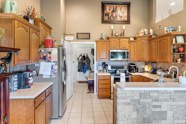 106 Finch Dr, Strafford, MO 65757 - kitchen with appliances with stainless steel finishes, light tile patterned floors, tasteful backsplash, light countertops, and a peninsula