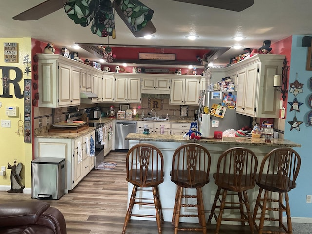 4811 State Route Cc, West Plains, MO 65775 - kitchen with stainless steel appliances, a peninsula, under cabinet range hood, light stone countertops, and a ceiling fan