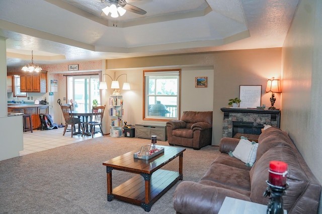 258 State Highway 32, Buffalo, MO 65622 - living room featuring ceiling fan, a tray ceiling, a stone fireplace, and light colored carpet