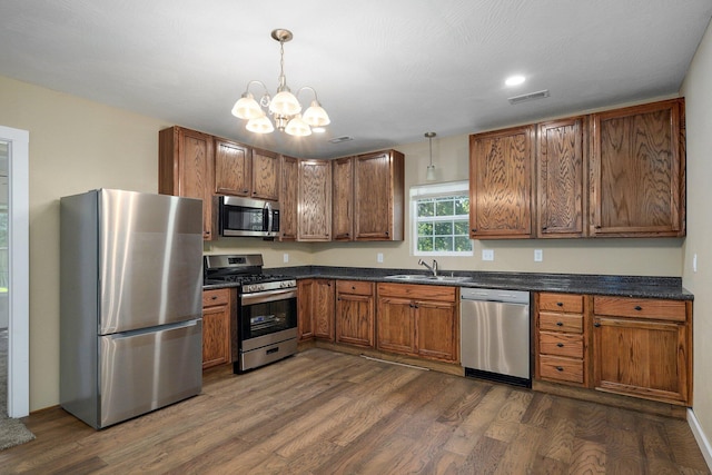 114 N Hobbs St, Miller, MO 65707 - kitchen featuring stainless steel appliances, dark countertops, dark wood-style floors, a chandelier, and brown cabinets