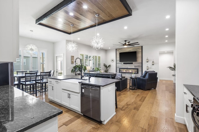 940 E Powers Ct, Nixa, MO 65714 - kitchen with dishwashing machine, a fireplace, a chandelier, a ceiling fan, and white cabinetry