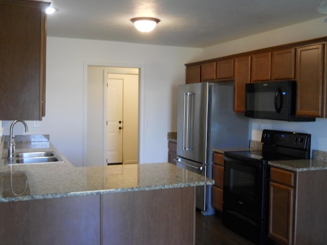424 Echo Valley Cir, Reeds Spring, MO 65737 - kitchen with black appliances, light stone counters, a peninsula, and brown cabinets