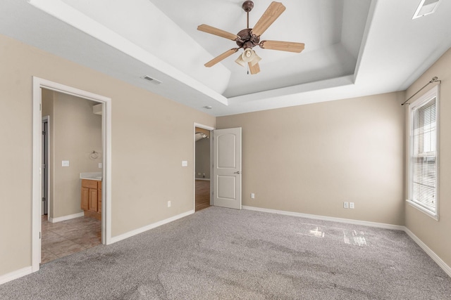 663 N Althea Ave, Nixa, MO 65714 - unfurnished bedroom with carpet, a tray ceiling, connected bathroom, and ceiling fan