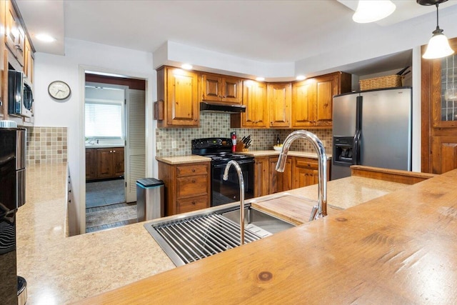 23 Sweetwater Ln, Buffalo, MO 65622 - kitchen featuring appliances with stainless steel finishes, under cabinet range hood, light countertops, brown cabinetry, and decorative backsplash