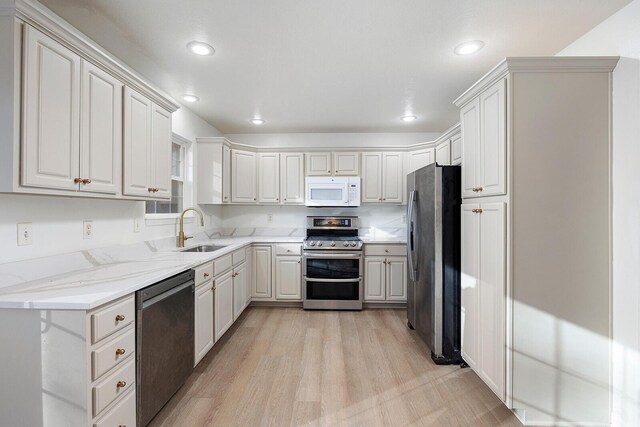 903 N 4th St, Ozark, MO 65721 - kitchen with stainless steel appliances, light wood-style flooring, light stone counters, recessed lighting, and white cabinetry