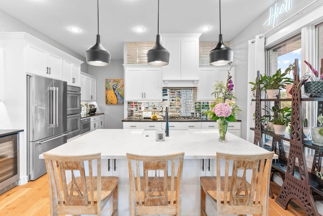 3972 E Dunrobin Dr, Springfield, MO 65809 - kitchen with appliances with stainless steel finishes, wine cooler, tasteful backsplash, a breakfast bar area, and white cabinetry