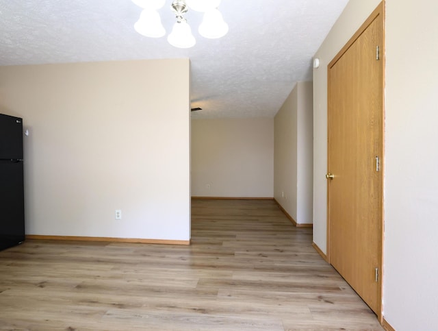 1324 N Forest Ave, Springfield, MO 65802 - empty room with a textured ceiling, a chandelier, and light wood finished floors